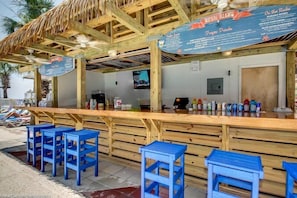 A beach bar with wooden seating and a menu board.