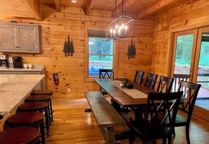 L’intérieur d’un chalet en bois comprend une cuisine, un coin repas et de grandes fenêtres.