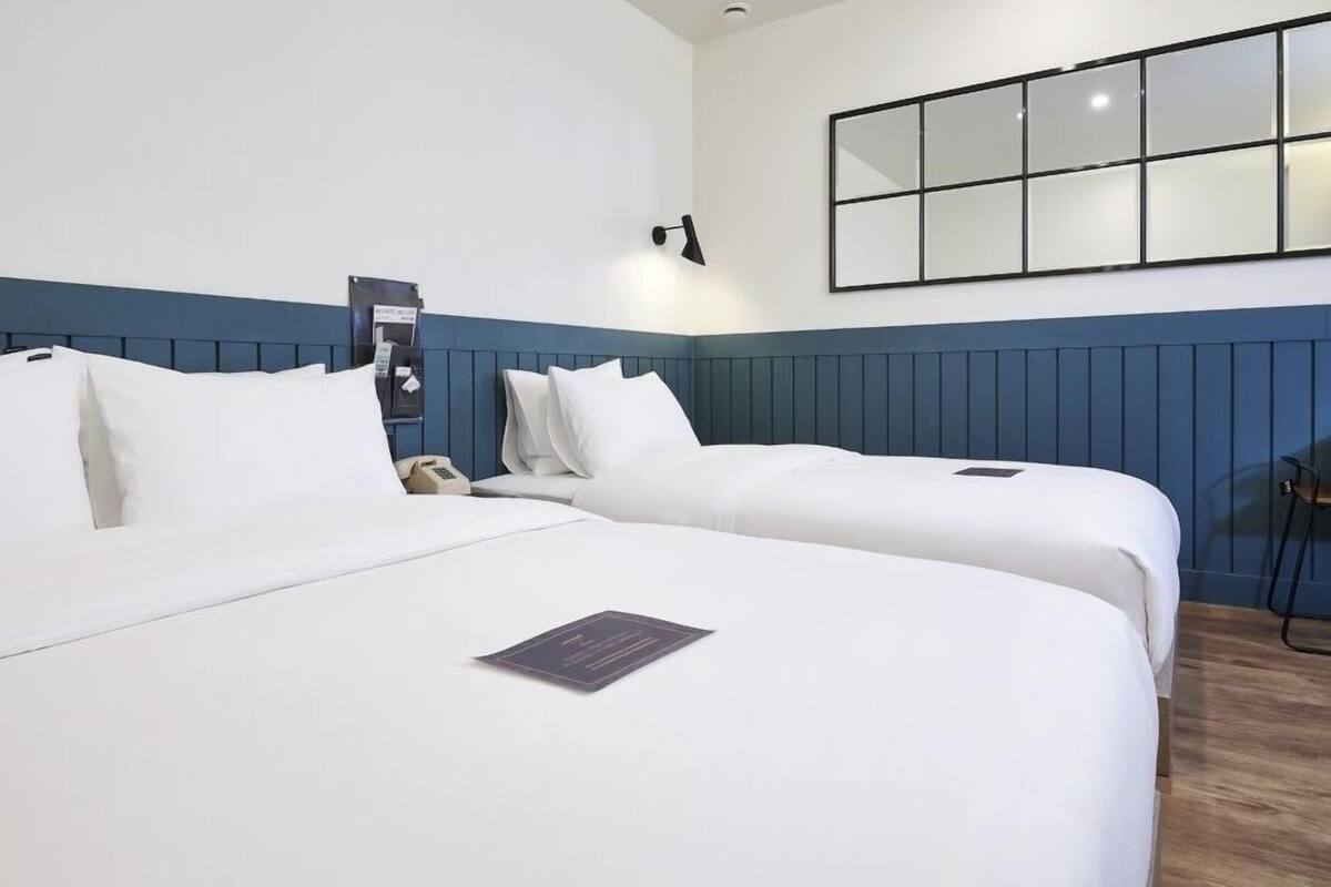 Habitació d'hotel amb dos llits, un escriptori, un mirall i un telèfon.