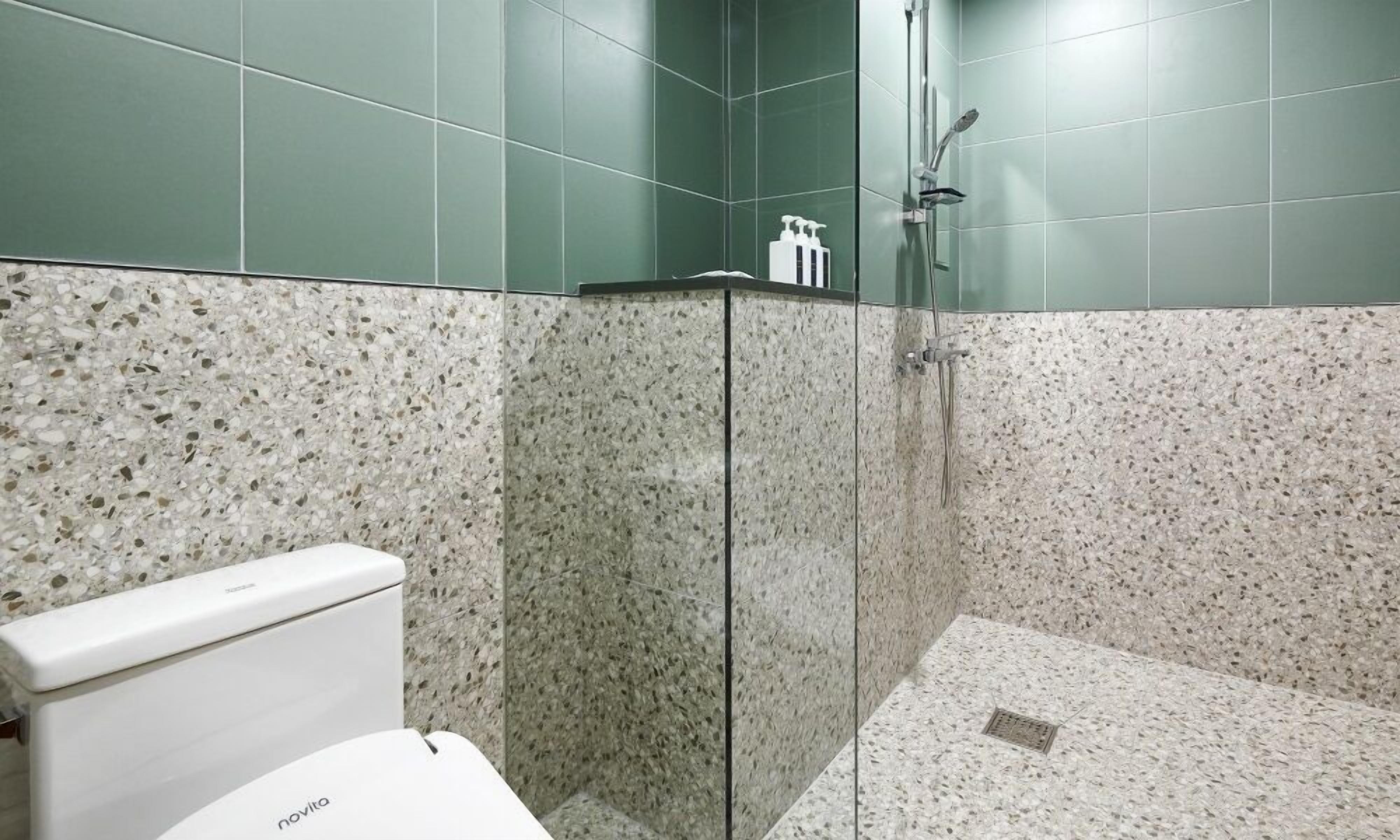 A bathroom with a toilet, a shower, and a glass-enclosed cabinet.