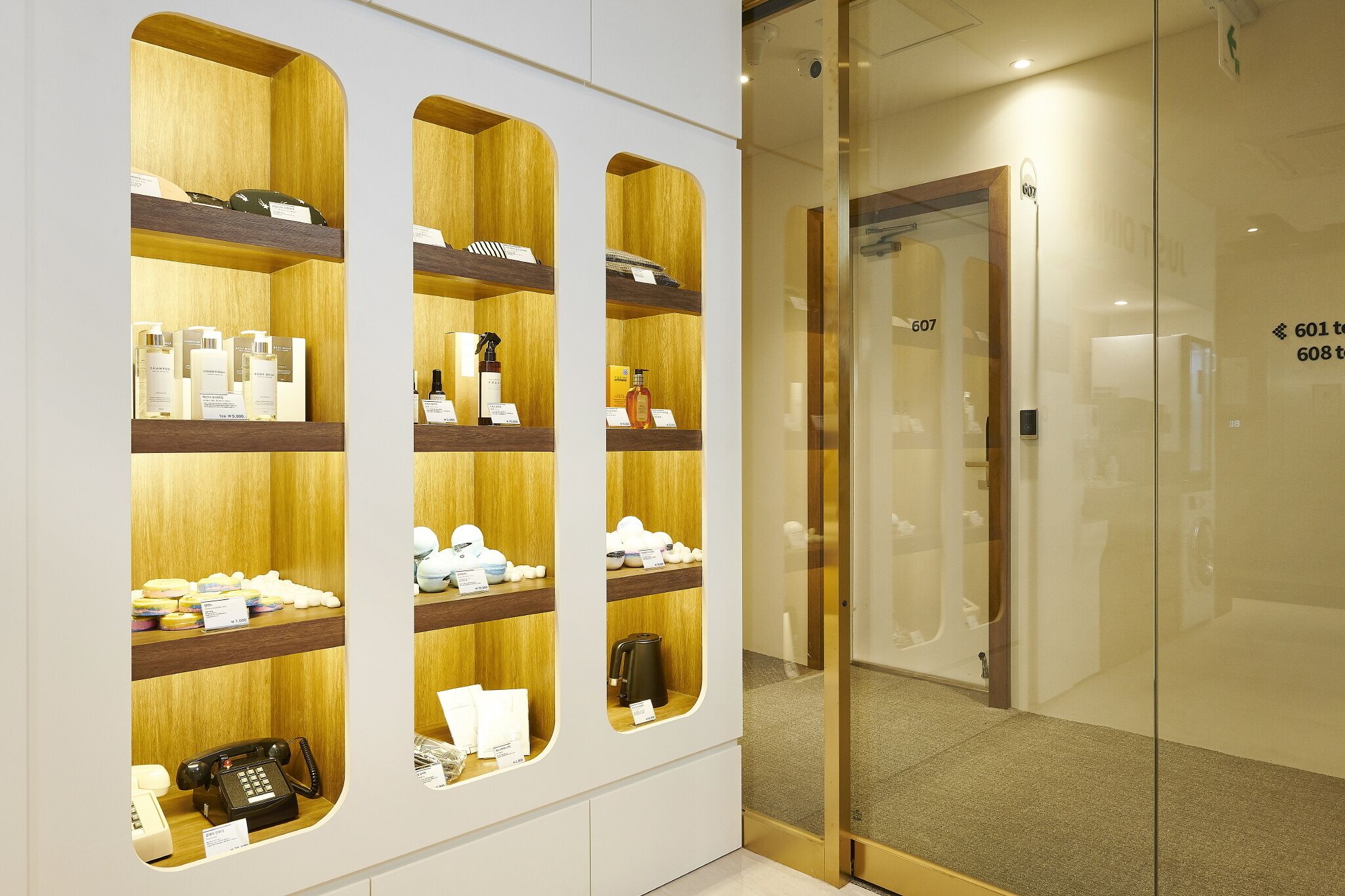 Zona de recepción de un hotel con un mostrador de madera, una puerta de cristal y un teléfono.