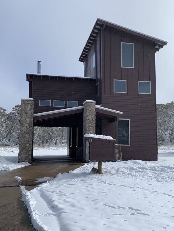 A two-story modern house with a stone foundation and a covered driveway. - Cliff Hanger-Dinner Plain (Dinner Plain)