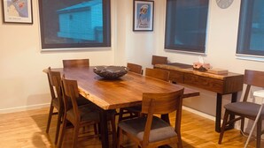 A dining area with a wooden table, chairs, and a large window. - Cliff Hanger-Dinner Plain (Dinner Plain)