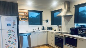 A modern kitchen with white cabinets, a dishwasher, a stove, and a coffee maker. - Cliff Hanger-Dinner Plain (Dinner Plain)