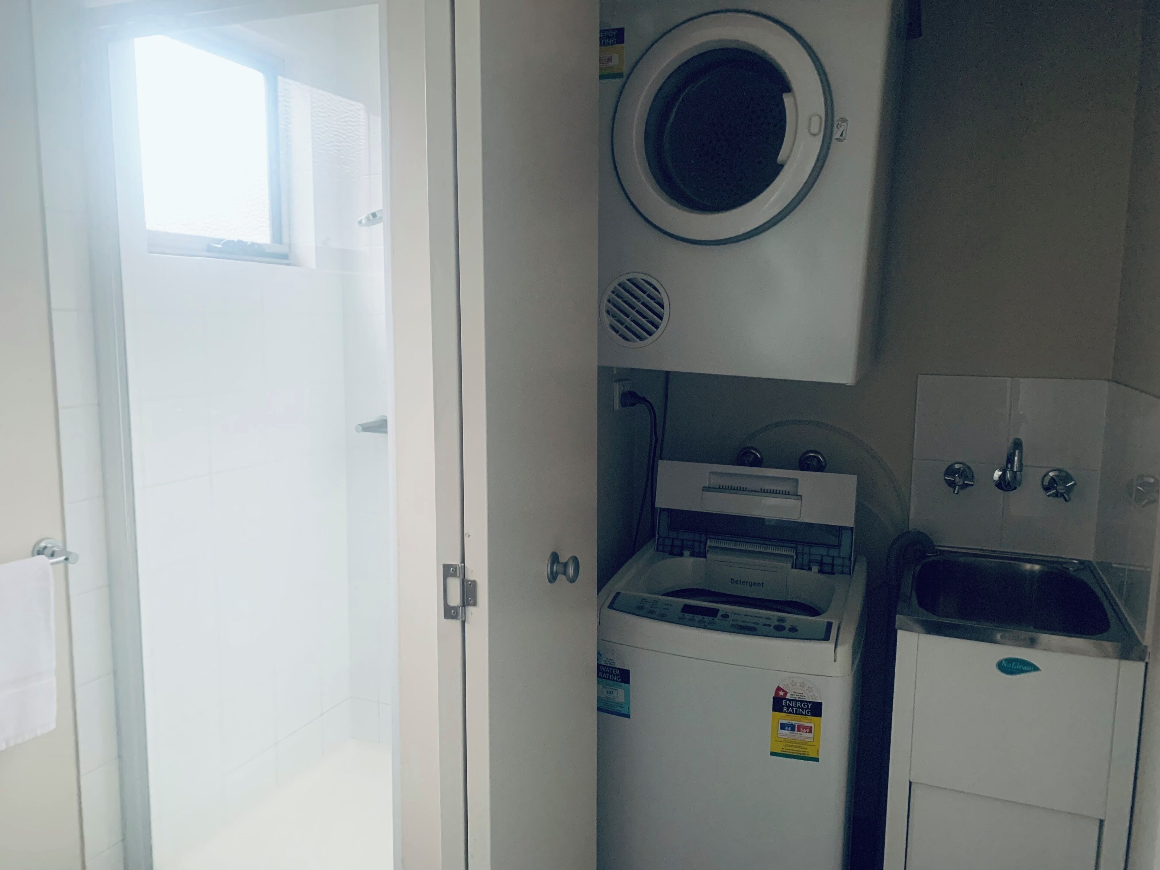 A compact kitchen with a built-in washer and dryer, a small sink, and a window above the door.