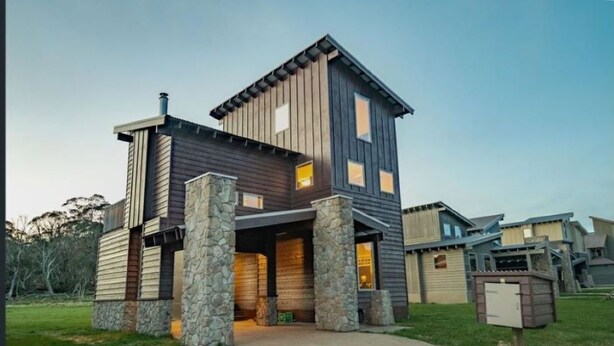 A modern two-story house with a stone foundation, a covered front porch, and a garage. - Cliff Hanger-Dinner Plain (Dinner Plain)