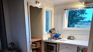 Kompakti keittiö, jossa on puuhella, sisäänrakennettu uuni ja pieni jääkaappi.