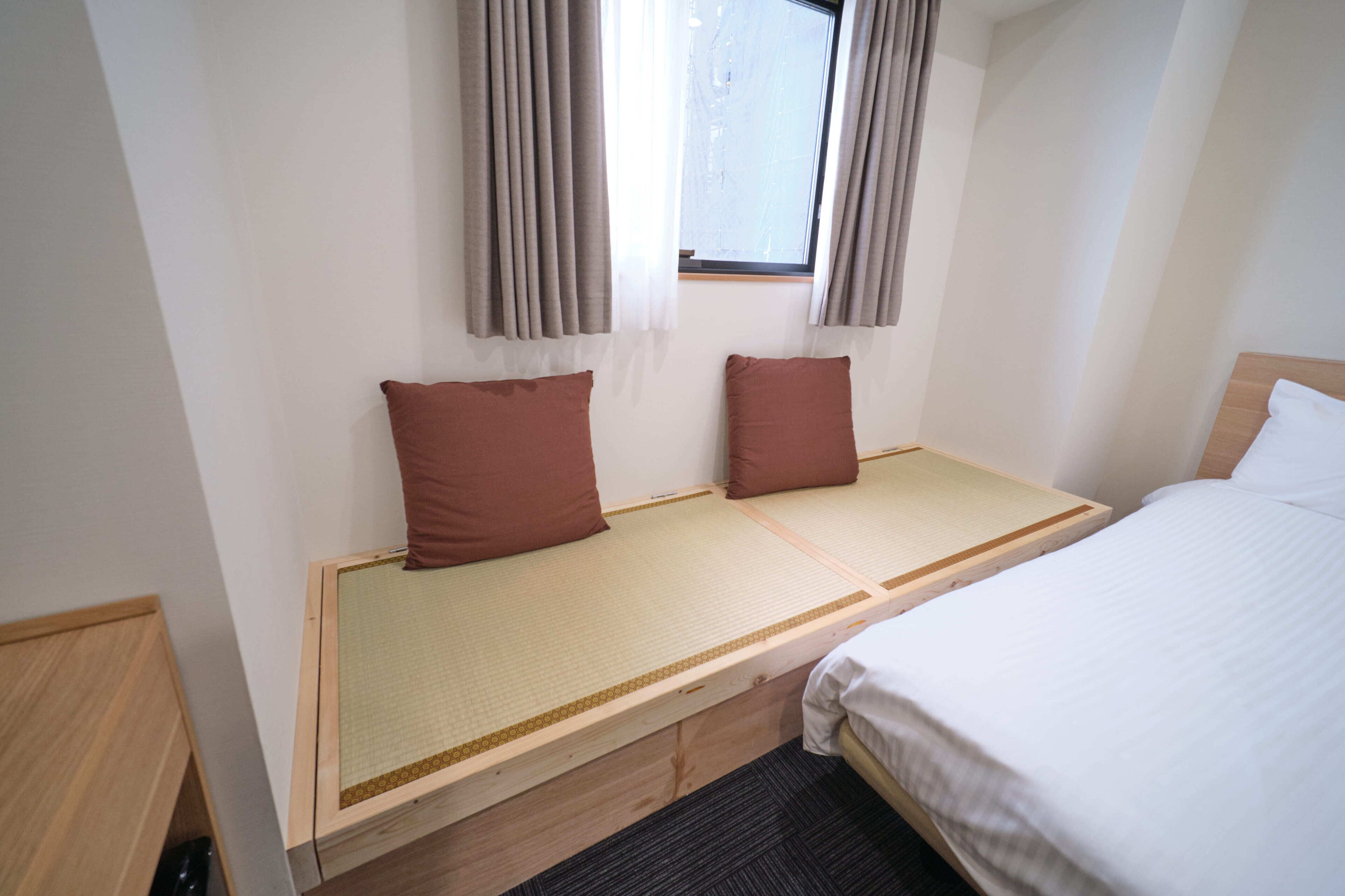 Una cama individual con cabecera de madera, una mesita de noche pequeña y dos almohadas.