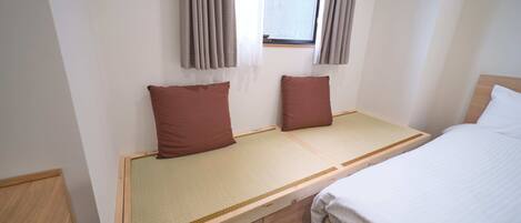 Una cama individual con cabecera de madera, una mesita de noche pequeña y dos almohadas.