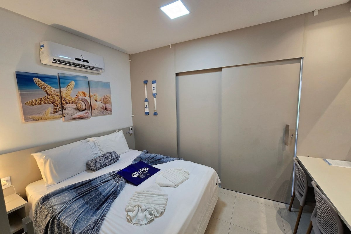 Ein Hotelzimmer mit einem Bett, einem Schreibtisch, einer Klimaanlage, einem Kleiderschrank und Wanddekorationen.