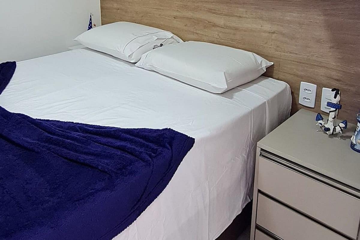 Ein Schlafzimmer mit einem Bett, einem Nachttisch, einem Kleiderschrank und einem hölzernen Kopfteil.