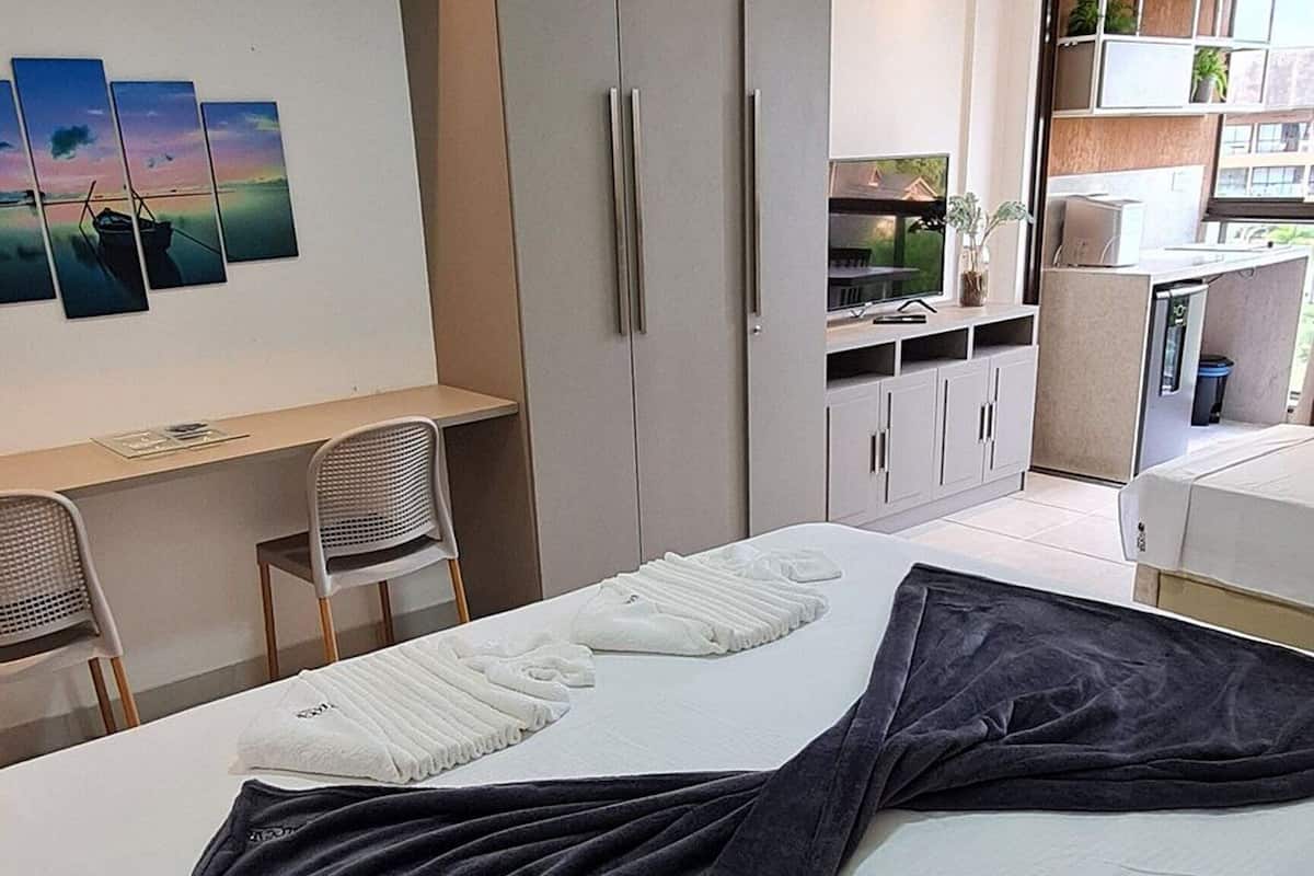 Ein modernes Hotelzimmer mit Bett, Schreibtisch und Kleiderschrank.
