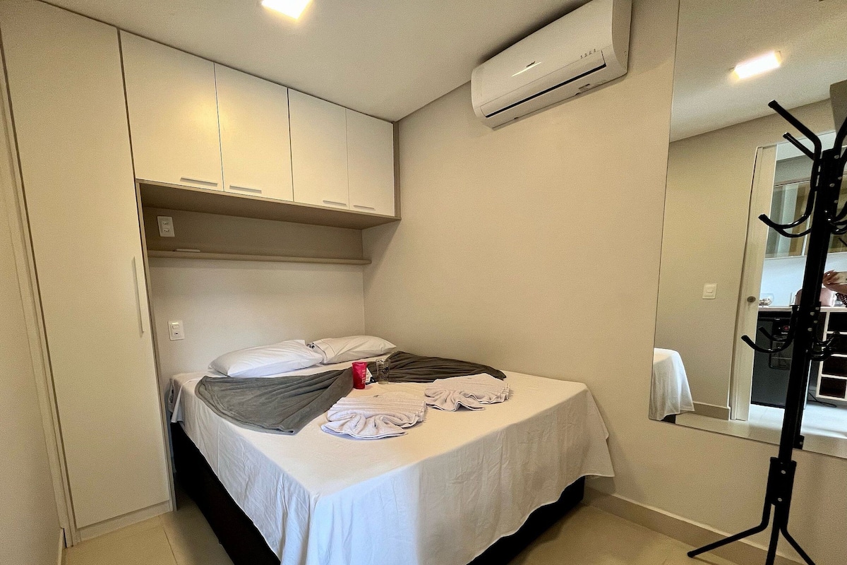 Ein kleines, ordentlich eingerichtetes Schlafzimmer mit Bett, Spiegel und Fenster.