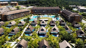 A resort with multiple bungalow-style accommodations, a central swimming pool, and lush greenery.
