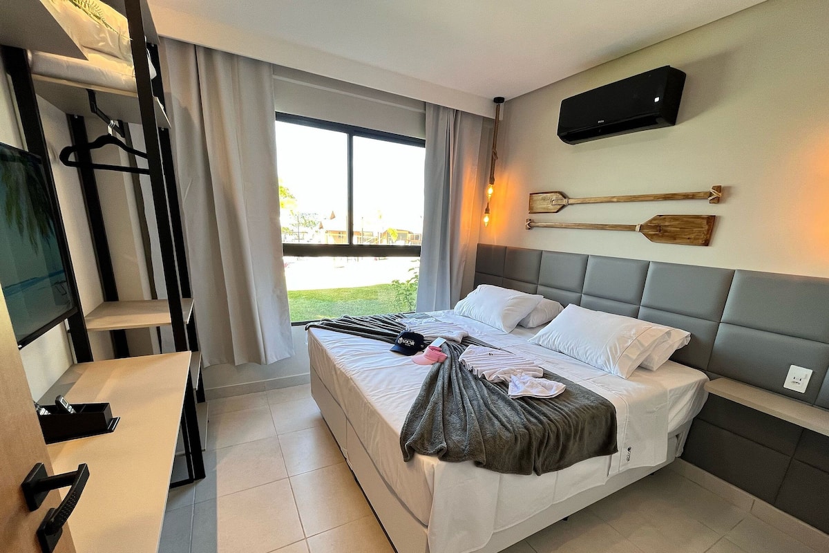 Ein modernes Hotelzimmer mit Bett, Schreibtisch, Fernseher und Blick ins Freie.
