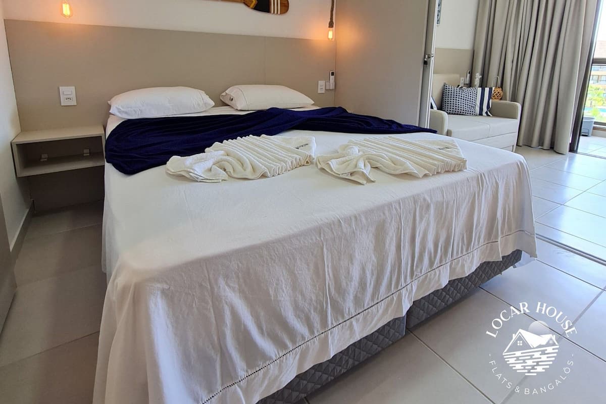 Ein Hotelzimmer mit Bett, einer Wandklimaanlage und Blick ins Freie.