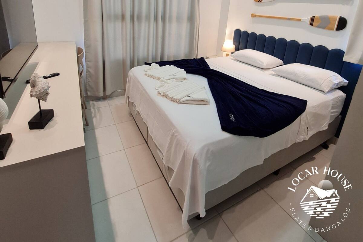 Ein Hotelzimmer mit einem Bett, einem Schreibtisch, einer Lampe und einem an der Wand befestigten Stand-Up-Paddle.