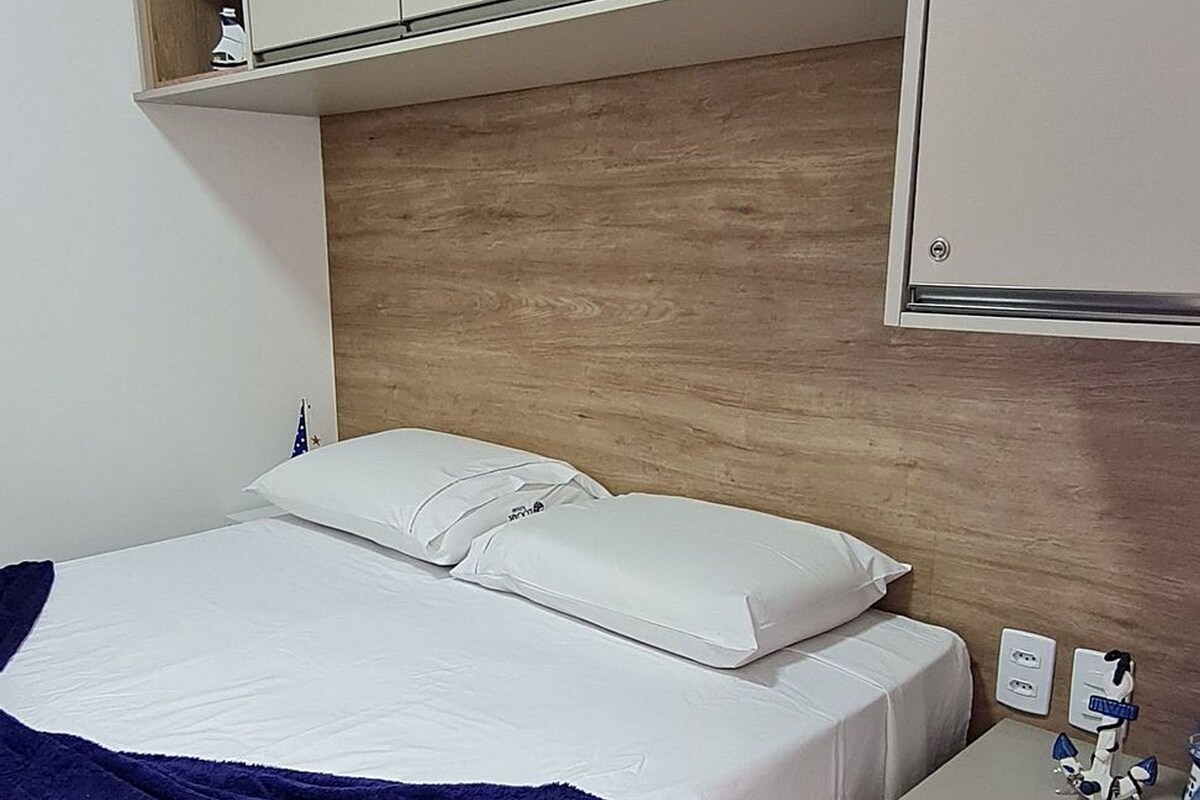 A bedroom with a bed, a nightstand, a wardrobe, and a wooden headboard.