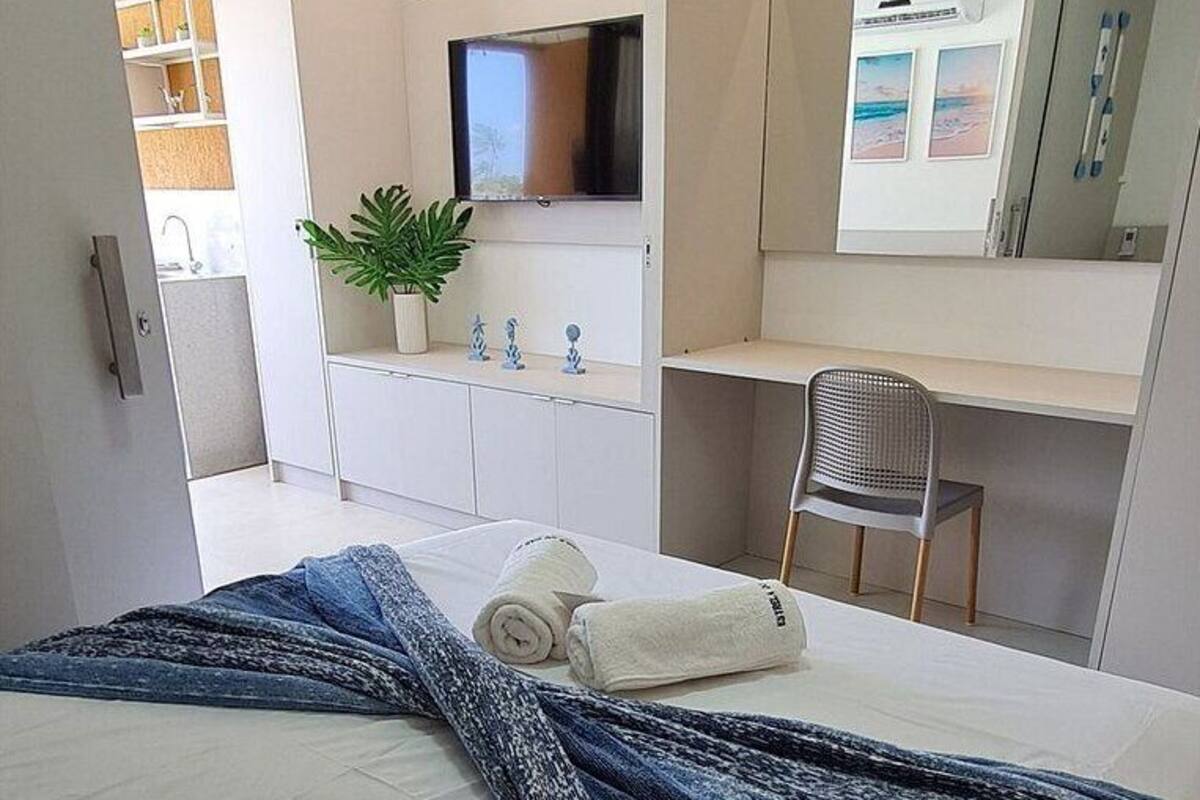 Ein modernes Hotelzimmer mit Bett, Schreibtisch, Stuhl, Fernseher und Spiegel.