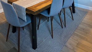 Un coin repas avec une table en bois, quatre chaises, une plante et une affiche accrochée au mur.