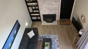 Un salon moderne avec une cheminée, un canapé noir et un téléviseur.