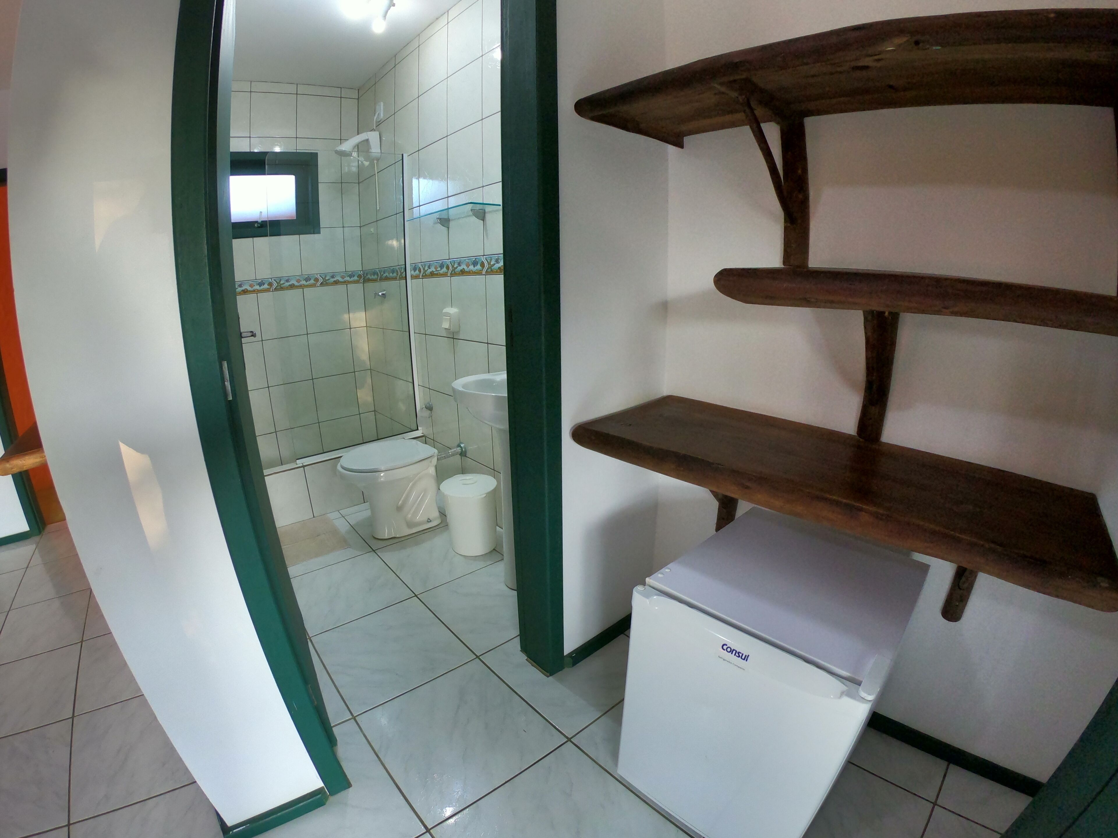A bathroom with a toilet, a sink, and a small white refrigerator.
