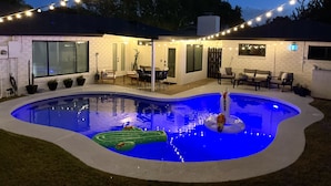 Ein Garten mit Swimmingpool, Lichterkette und Gartenmöbeln.