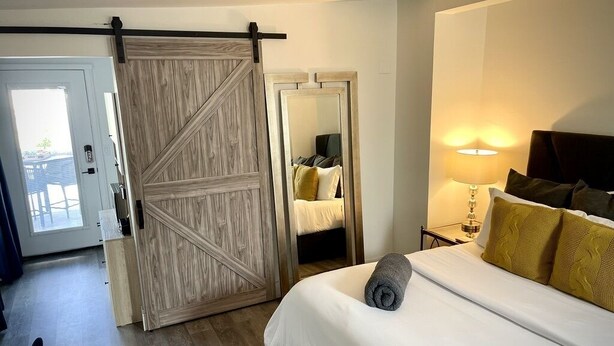 Ein Hotelzimmer mit einem Bett, einem Nachttisch mit Lampe, einer Schiebetür und einem Spiegel.