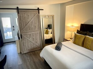 A hotel room with a bed, a nightstand with a lamp, a sliding door, and a mirror. - Private Mother-in-law suite with separate entrance (Phoenix)