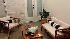 Eine gemütliche Sitzgelegenheit im Freien mit zwei Sofas, zwei Sesseln, einem kleinen Tisch und einem Blumentopf.