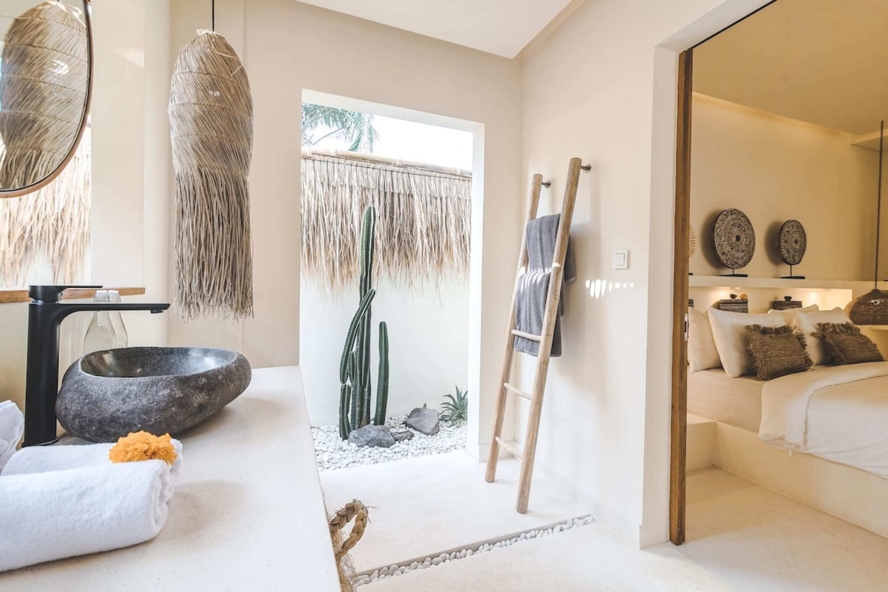 A modern bathroom with a stone basin, a towel, and a hanging light fixture.