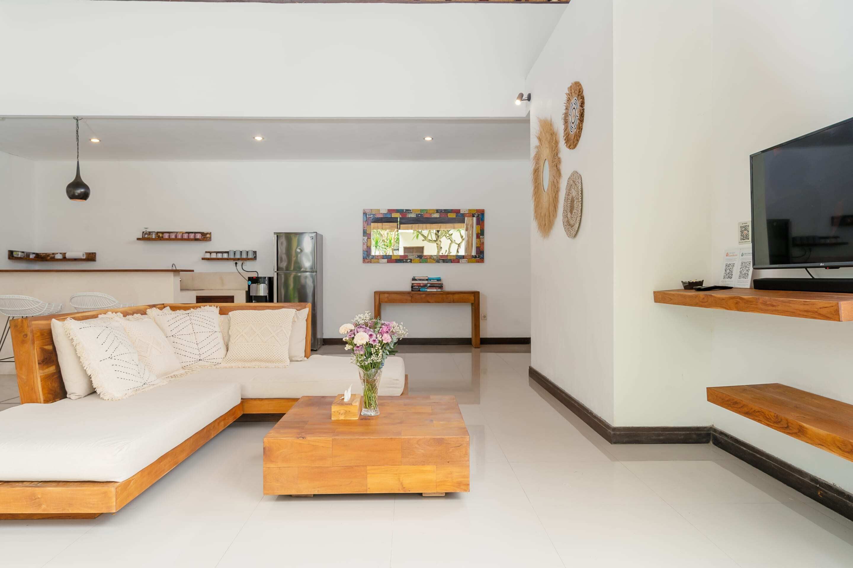 A modern living room with a sectional sofa, a wooden coffee table, a flat-screen TV, and decorative wall art.