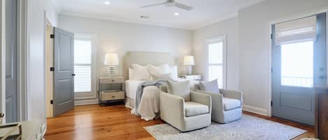 Une chambre à coucher comprenant un lit, deux tables de chevet, une chaise, un tapis et un ventilateur de plafond.