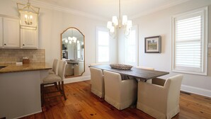 A modern kitchen with a wooden island, white cabinetry, and a dining area with a dark wood table and cushioned chairs. - Charming Oxford Townhome - Minutes to Ole Miss and The Square!  Sleeps 1-10 (Oxford)
