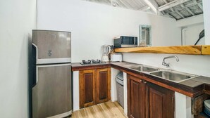Cocina compacta con refrigerador de acero inoxidable, microondas, tostadora y armarios de madera.