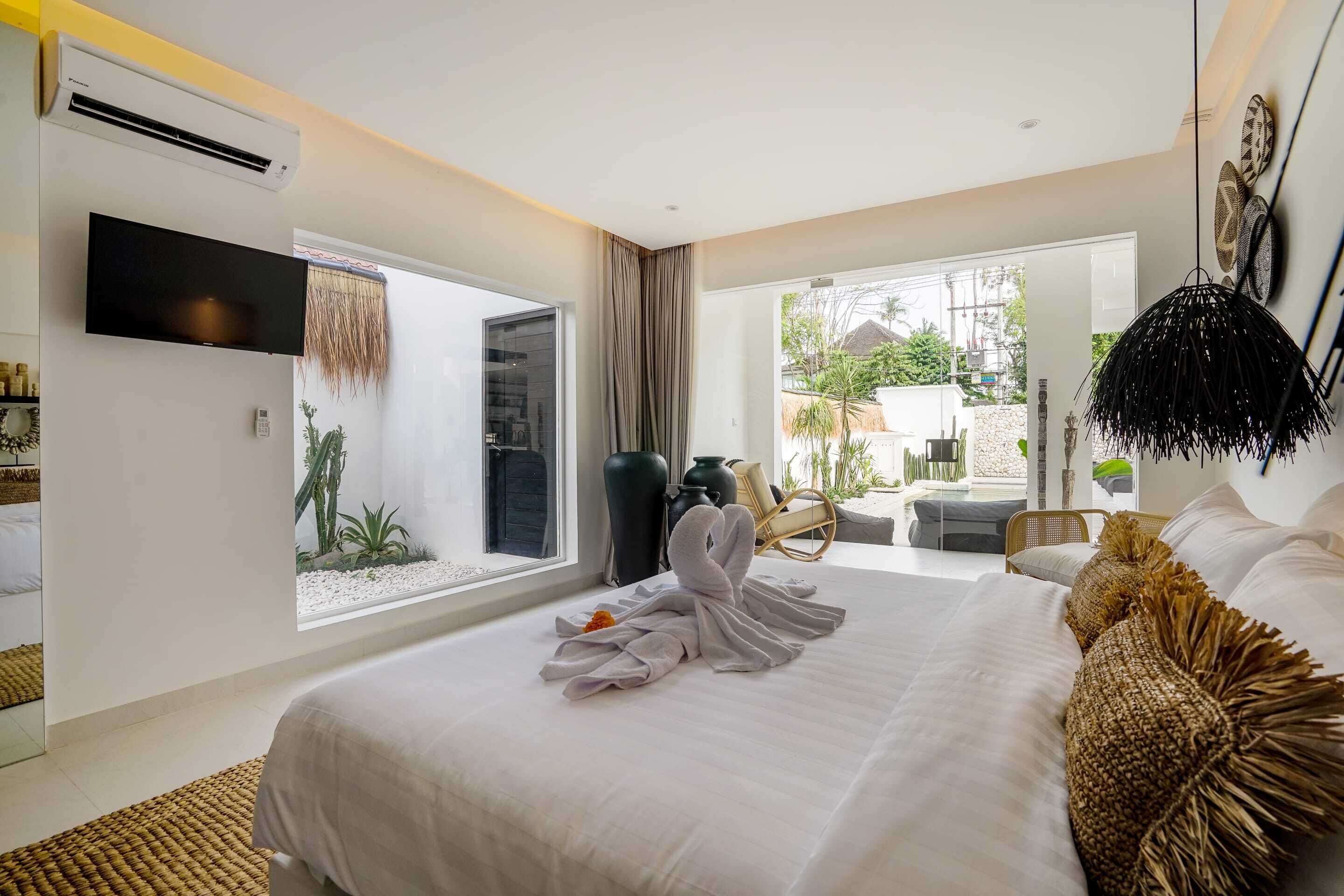 Quarto de hotel moderno com uma cama grande, televisão de tela plana, janela ampla e vista para o exterior.