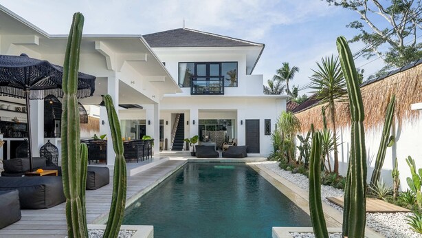 Una casa moderna con piscina, mobiliario exterior y cactus.
