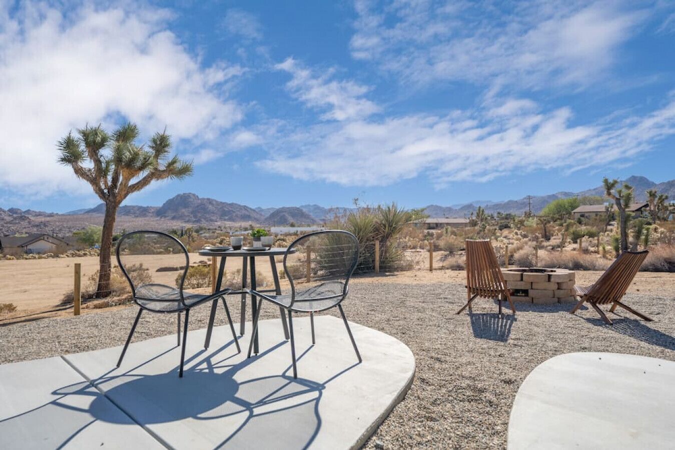 A patio with a table and chairs, a fire pit, and a view of mountains.