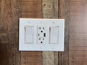 Un enchufe blanco con dos interruptores y un puerto USB sobre una superficie de madera.