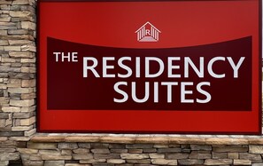 A sign for 'The Residency Suites' with a logo above the text.