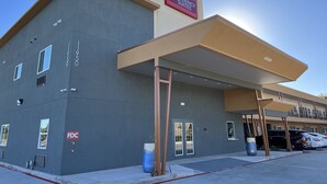 A modern building with a sign for 'The Residency Suites'. It features a flat roof, large windows, and a covered entrance area. - The Residency Suites (Sugar Land)