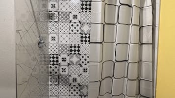 A shower with a patterned tile wall and a geometric shower curtain.