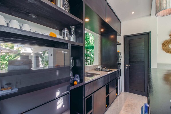 Una cocina moderna con armarios oscuros, horno empotrado y un amplio ventanal con vistas a zonas verdes.