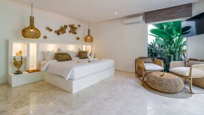 Quarto moderno com uma cama grande, mesas de cabeceira, um sofá e uma televisão.