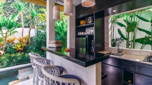 Cozinha moderna com bancada preta, banquetas e vista para vegetação exuberante.