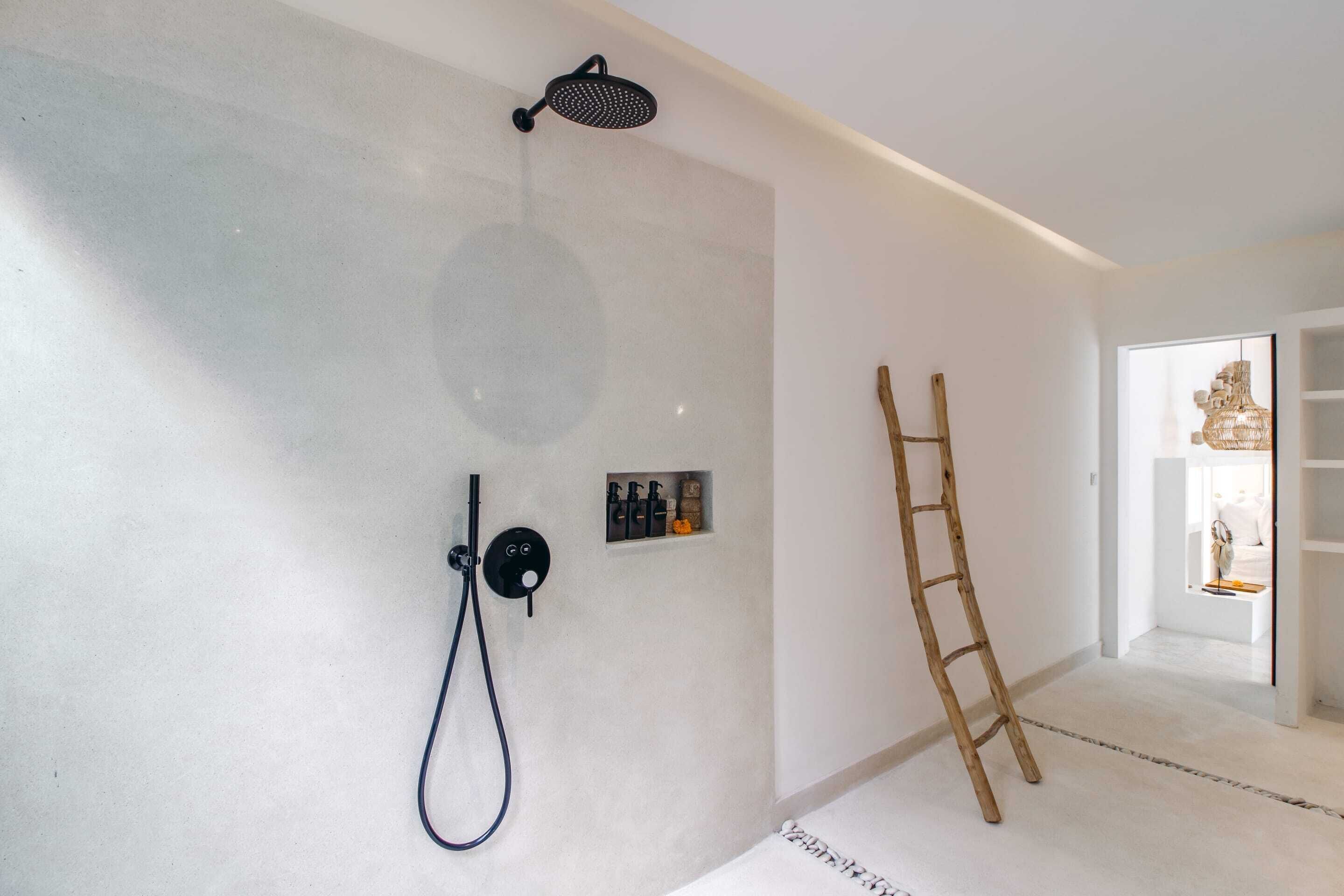 A modern bathroom with a shower, a towel rack, and a small shelf with toiletries.