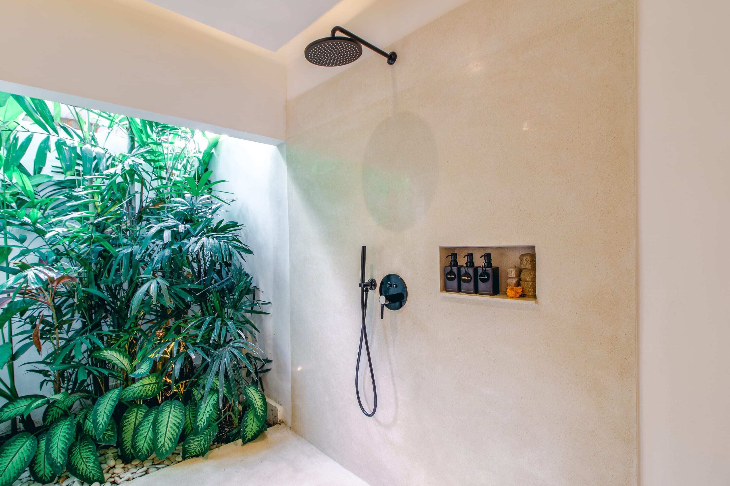 Ein modernes Duschbad mit Regendusche, Handbrause und einer kleinen Ablage für Pflegeprodukte.