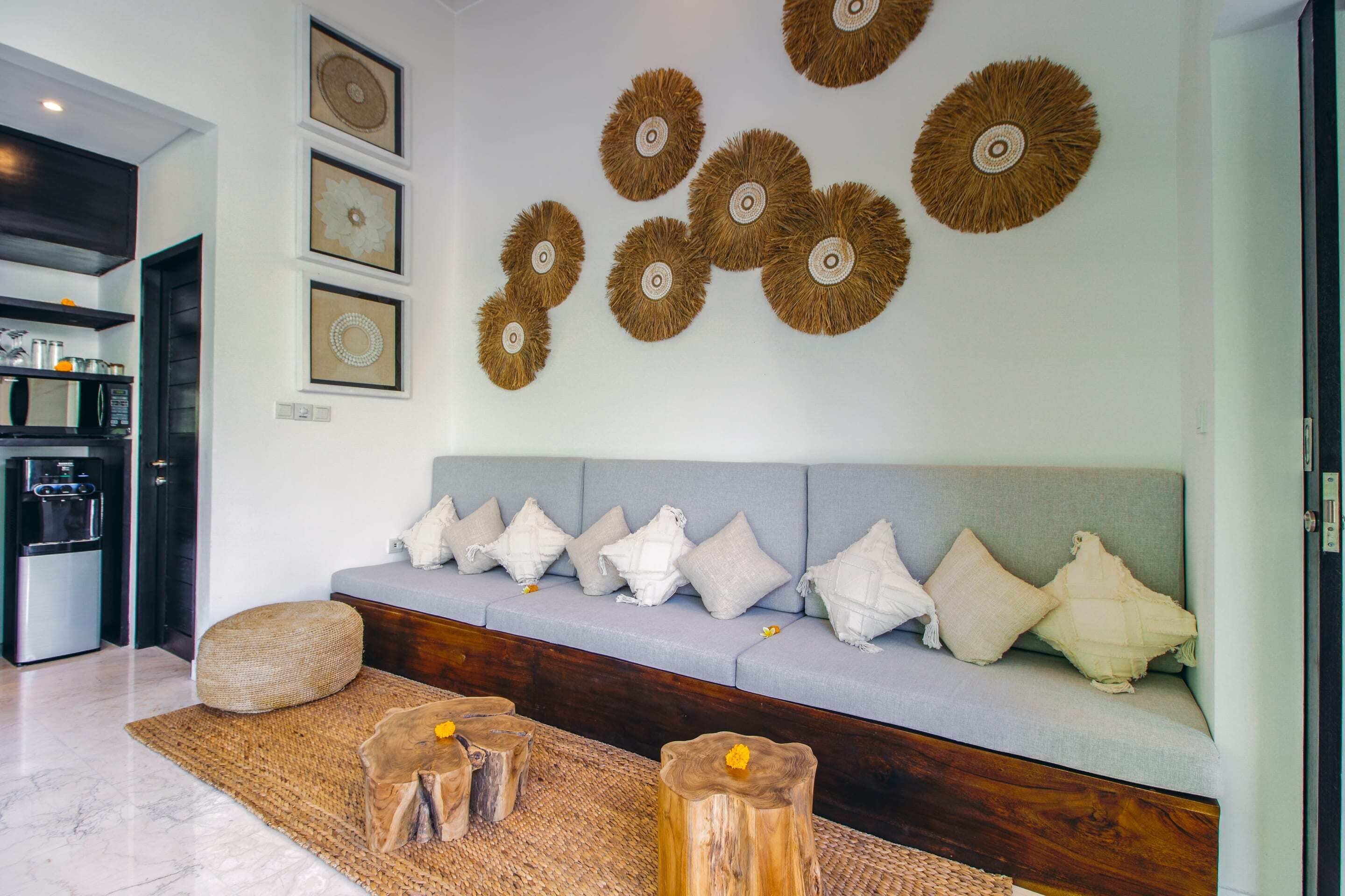 Un salon moderne avec un canapé gris, des tabourets en bois et des œuvres d’art décoratives accrochées au mur.