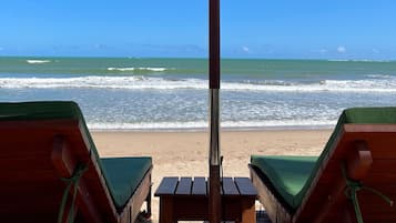 En la playa, arena blanca, sillas reclinables de playa, sombrillas