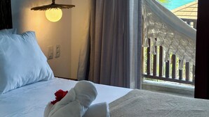 Une chambre d’hôtel avec un lit, un luminaire suspendu, une vue sur l’océan et un balcon doté d’une balustrade.